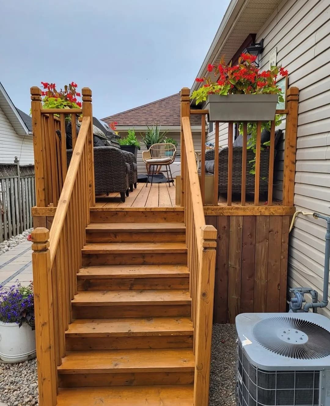 Finished deck stairs stained a warm cedar colour with skirting and stone below