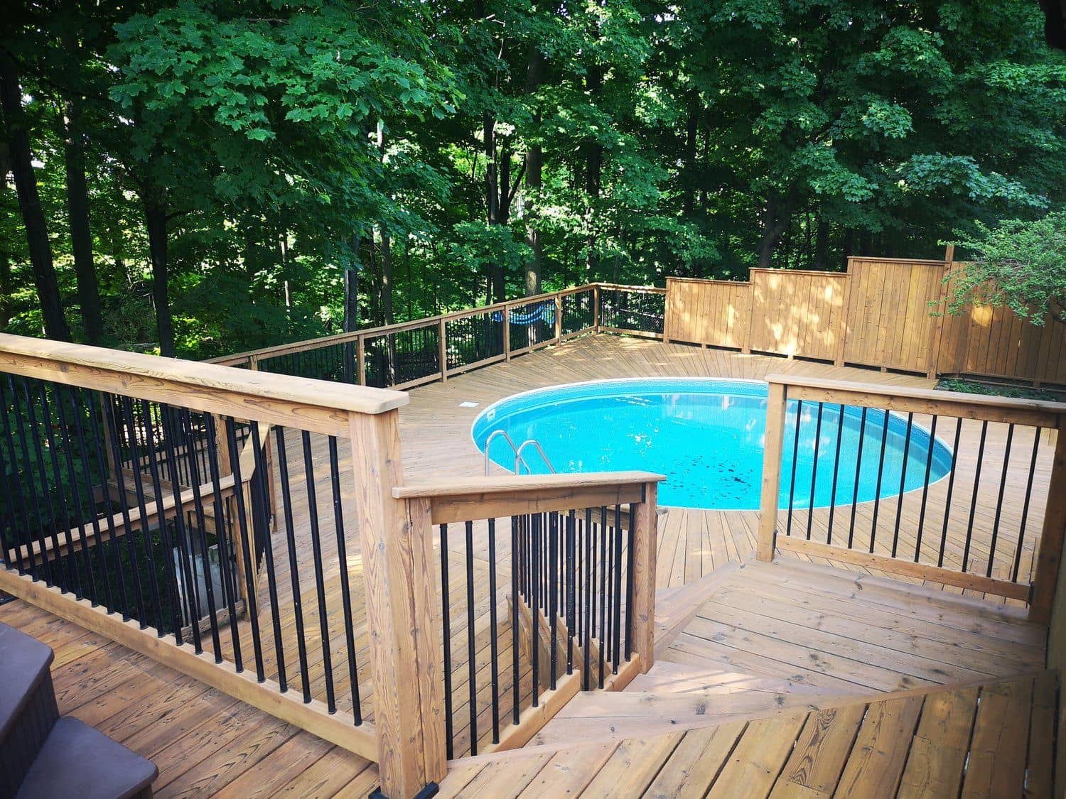 Restored cedar pool deck with black balusters, stained by OakRidge Stain Co.