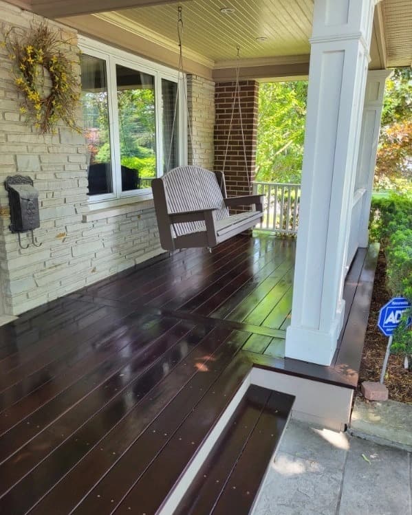 Dark stained hardwood porch floor with a white column